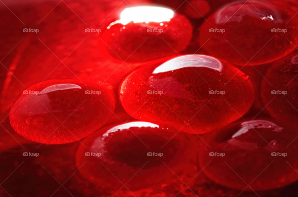 Bright red jelly-like globules in aqueous solution, with trapped air pockets.