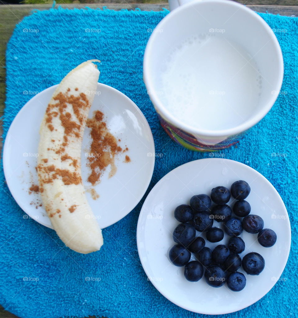 Ingredients for a morning smoothie- banana with cinnamon, blueberries and coconut milk