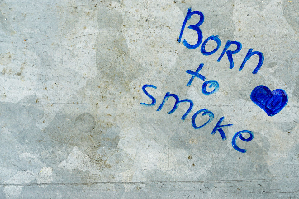 an inscription Born to smoke on a gray metal surface