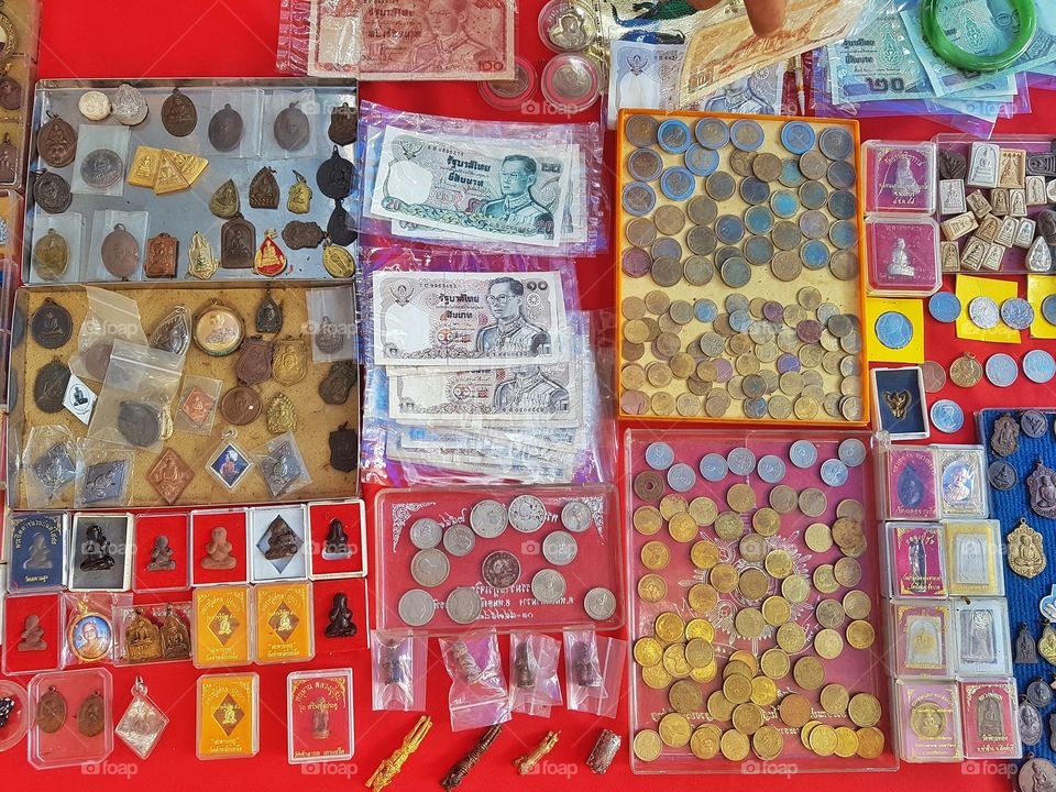 stall of antique buddhist amulet, coins and bank note, money in Thai currency at a flea market