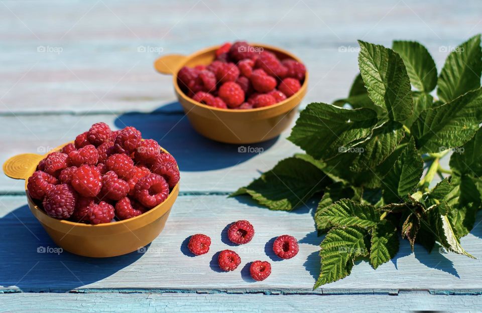 ripe raspberries in a mug on a blue wooden background