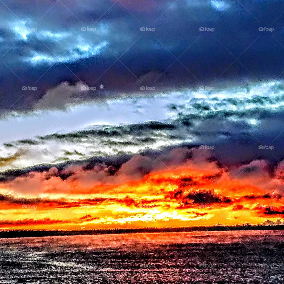 Bright Orange Sunset over lake Michigan from the upper peninsula of Michigan stormy blue skies above