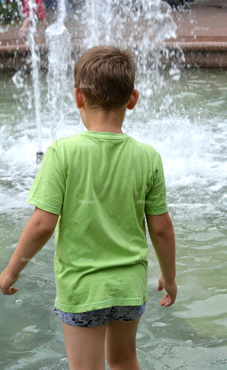 child in water fountain city summer time