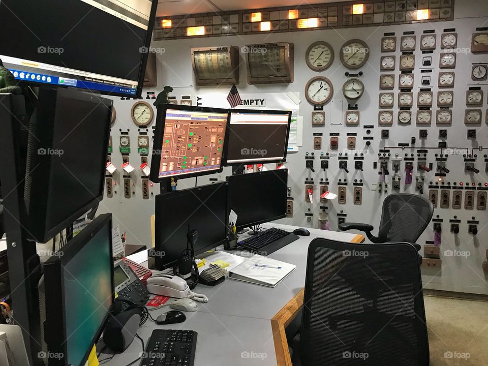 Control room inside an older electrical power plant with lots of gauges, dials, and control panels