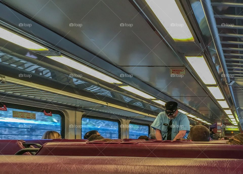 Train conductor collecting passenger tickets on our train ride out of Boston.  The train car was full and he was busy. 