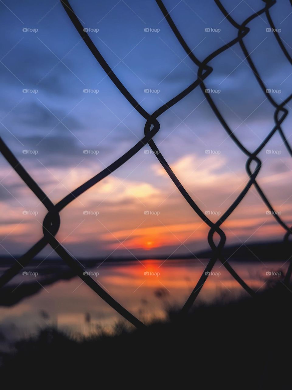 Metal fence in the form of rhombuses.  Sunset sky. Geometric shapes