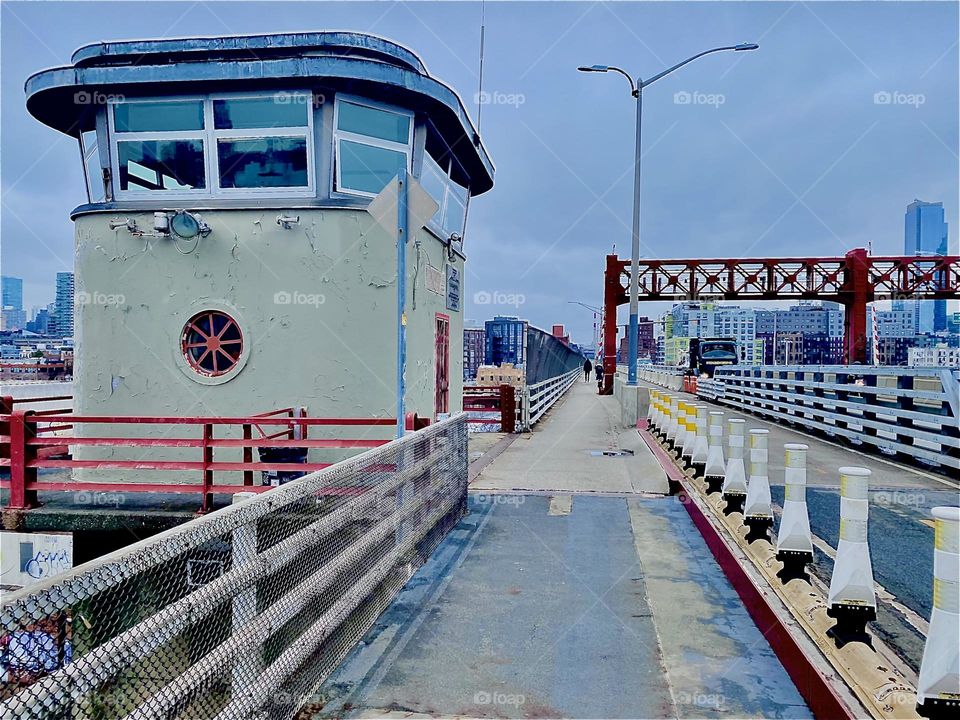 The tower in the middle of the “Pulaski Bridge” always has personale in it in part to open and close the bridge should a boat not fit underneath. 2023. Hypnotic Productions