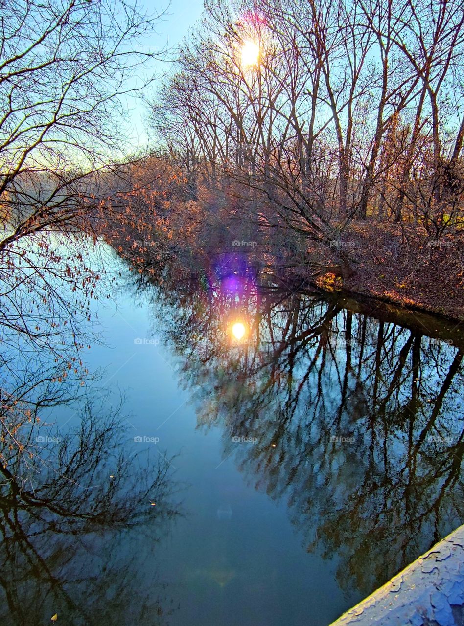 Late fall.  Reflection.  A river that reflects autumn trees, blue sky and sun
