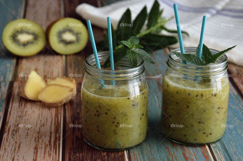 Kiwi smoothie on table with paper straw
