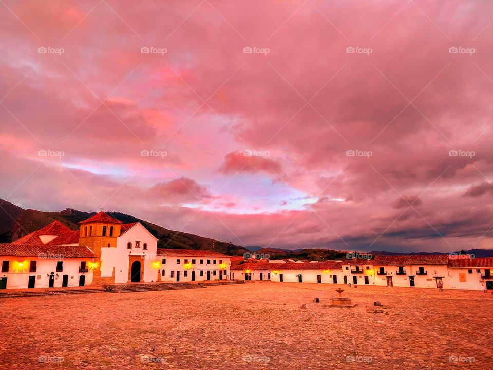 Amanecer de nubes rosadas en la plaza principal de Villa de Leyva Boyacá Colombia Sur America.Sunrise of pink clouds in the main square of Villa de Leyva. Beautiful destination, vibrant color landscape horizontal