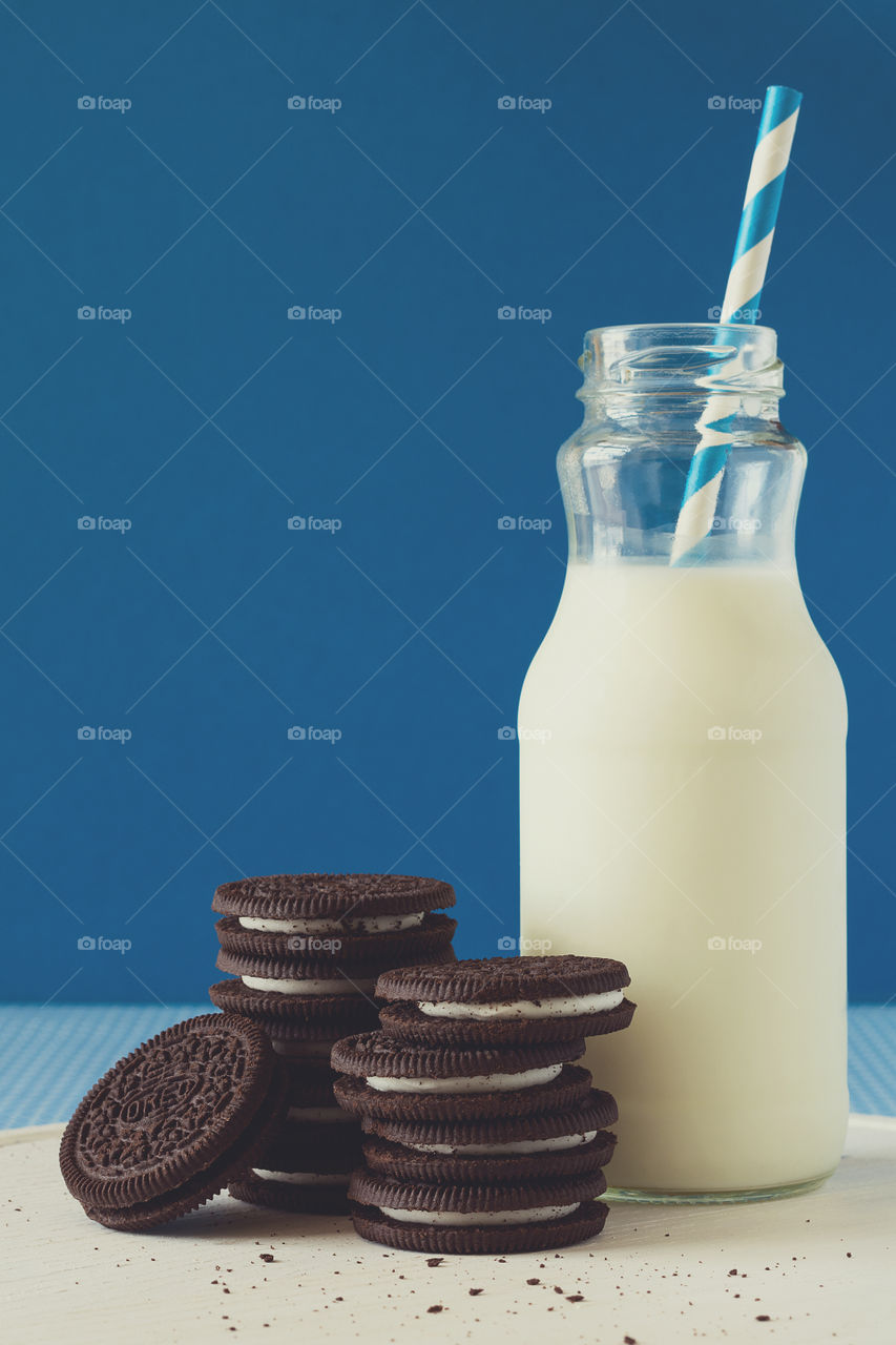 Oreo cookies and milk on blue background