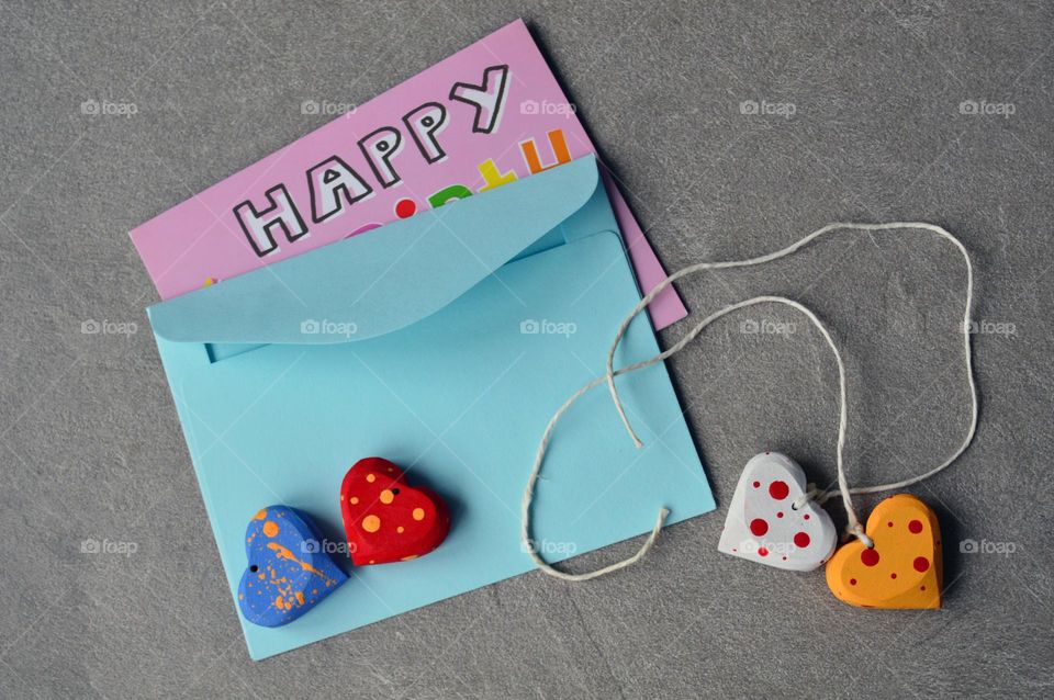 Multicolored wooden hearts near a greeting card