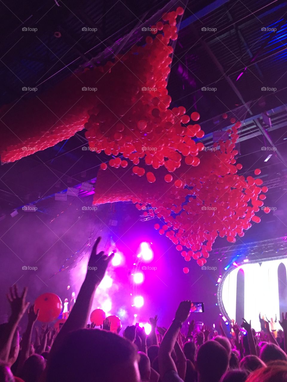 a lot of red balls fly from the ceiling at a concert