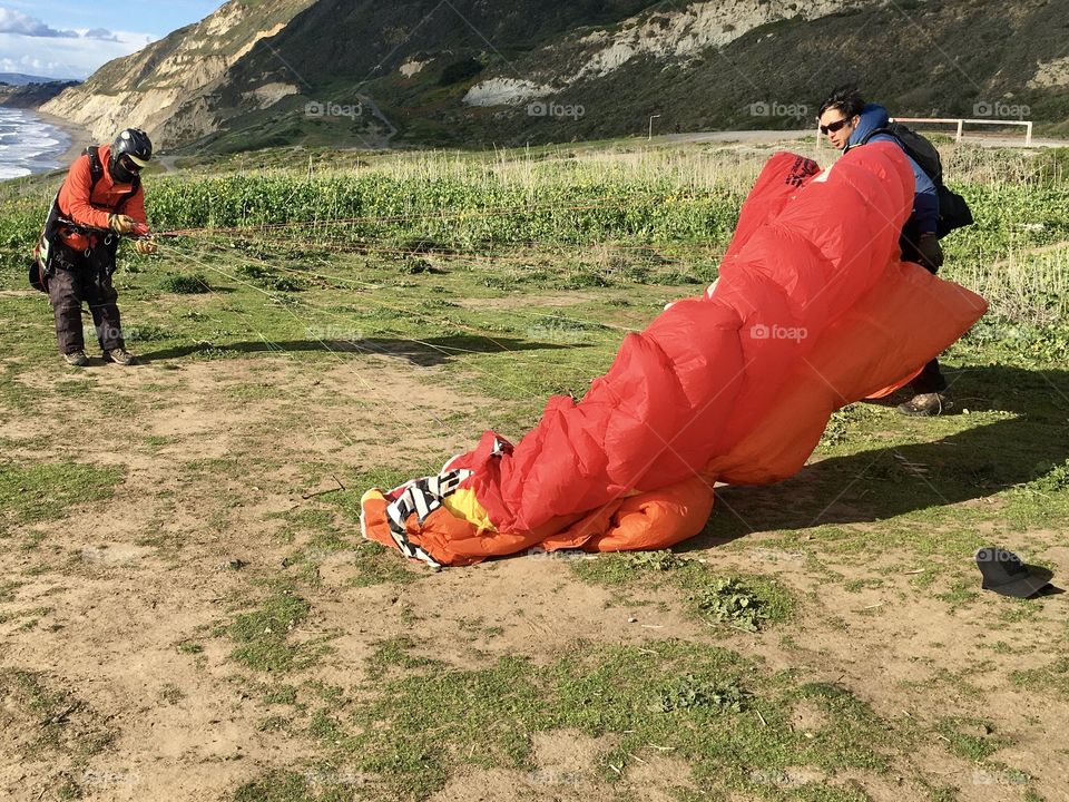 Two man opening red parachute