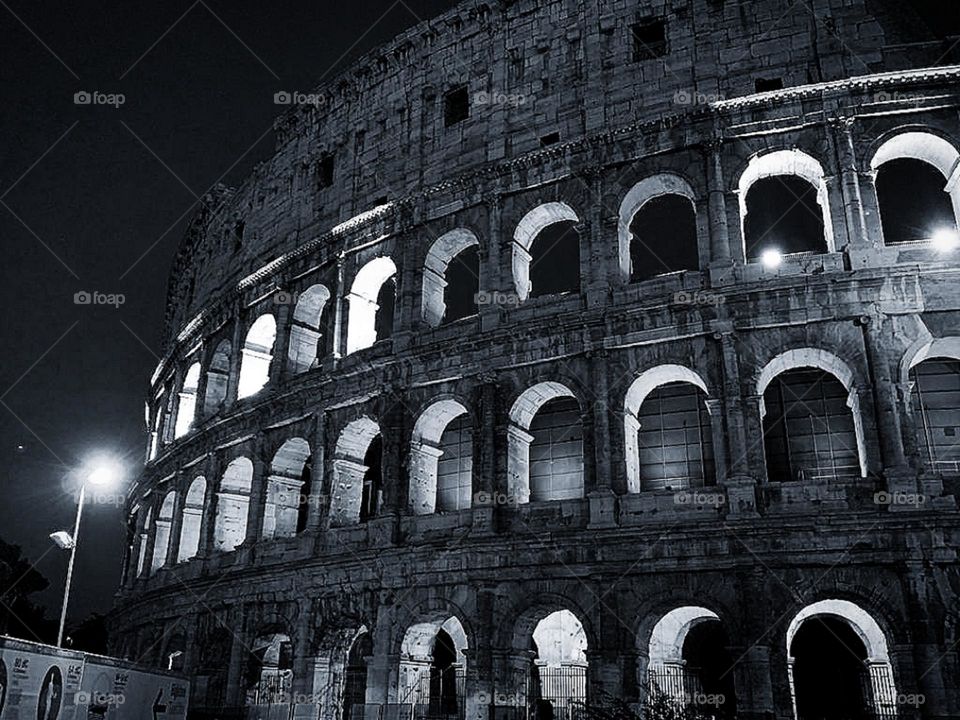 B&W. Italy. Rome. Part of the Colosseum at night. The Colosseum is illuminated by street lights and interior lighting. Monument of architecture and history of the country