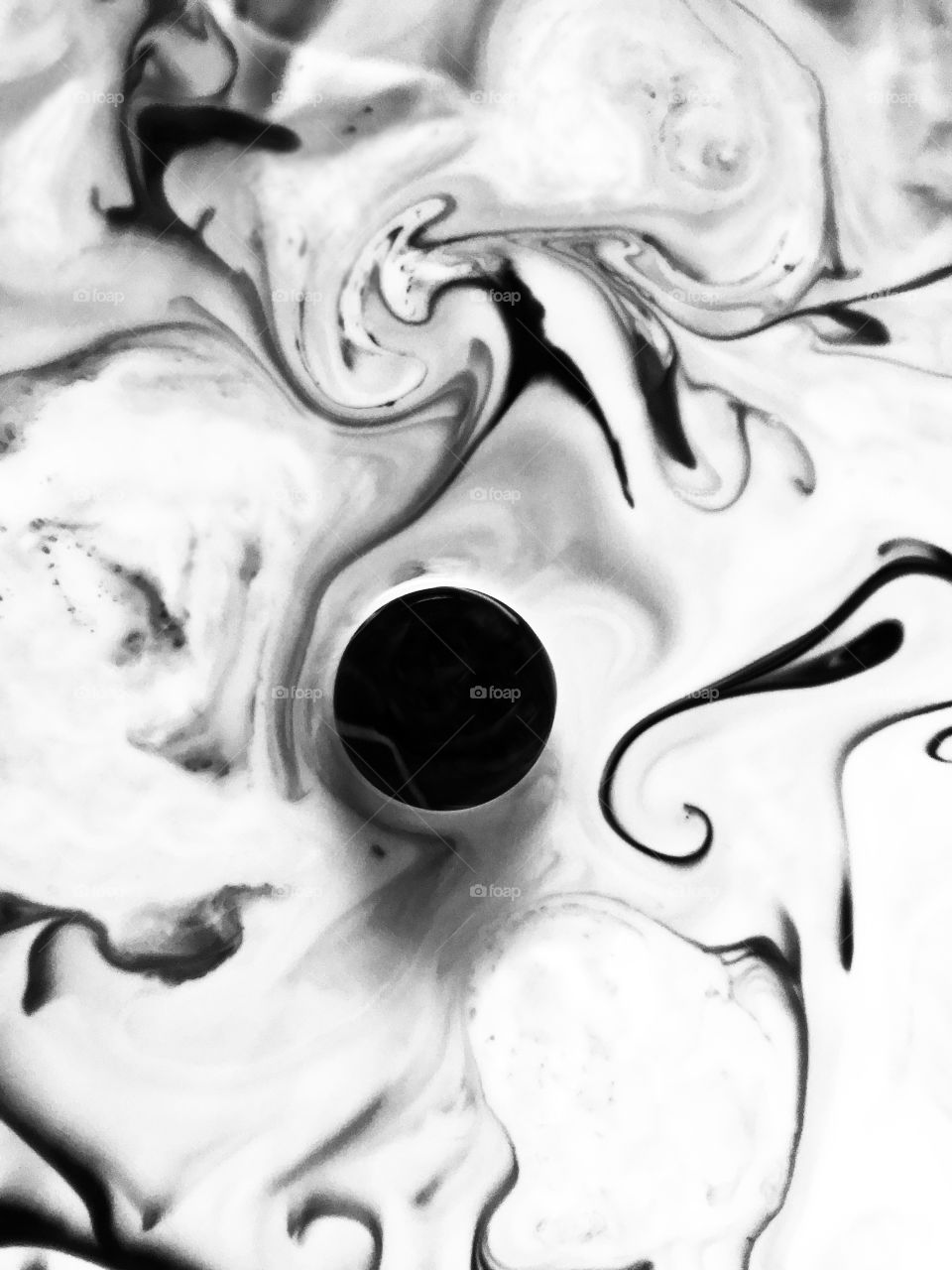 Minimalist abstract B&W of a dark marble in white milk and swirls of black ink. 