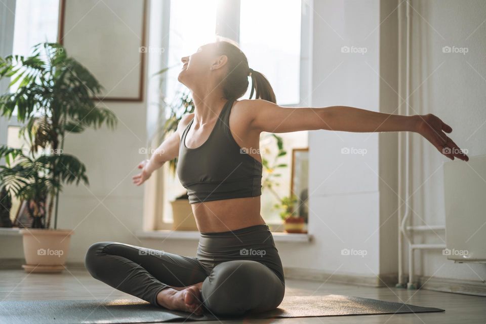 Young fit woman practice yoga in light yoga studio with green house plant