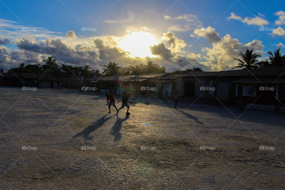 kids playing soccer on the street at sunset