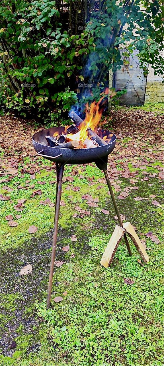 The bonfire is starting to burn in this stand alone cast iron fire bowl at the “Market of Possibilities” in the garden and apple orchard of the old castle of “Steinach” in “Lower Bavaria”, Germany. 2024. Hypnotic Productions