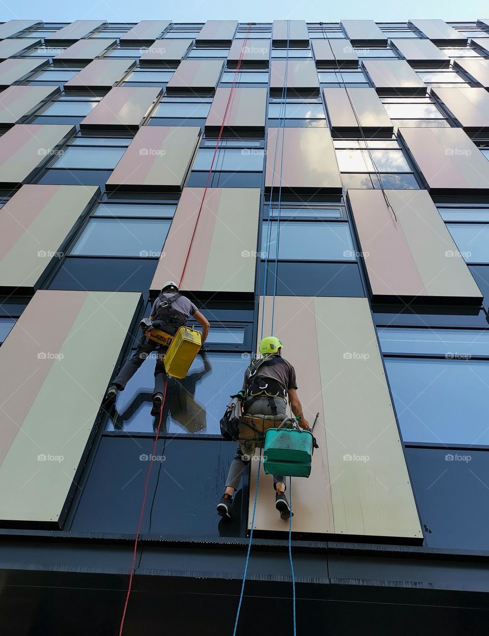 Two men wash windows in a multi-storey building.