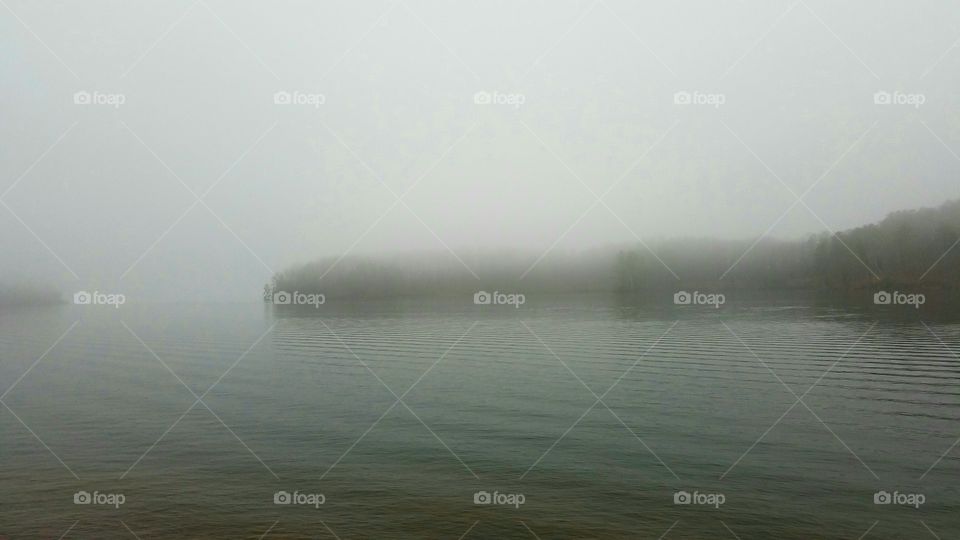 foggy morning with waves on the lake.