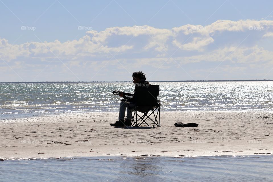 Solo musician performing alone surrounded by glistening ocean 