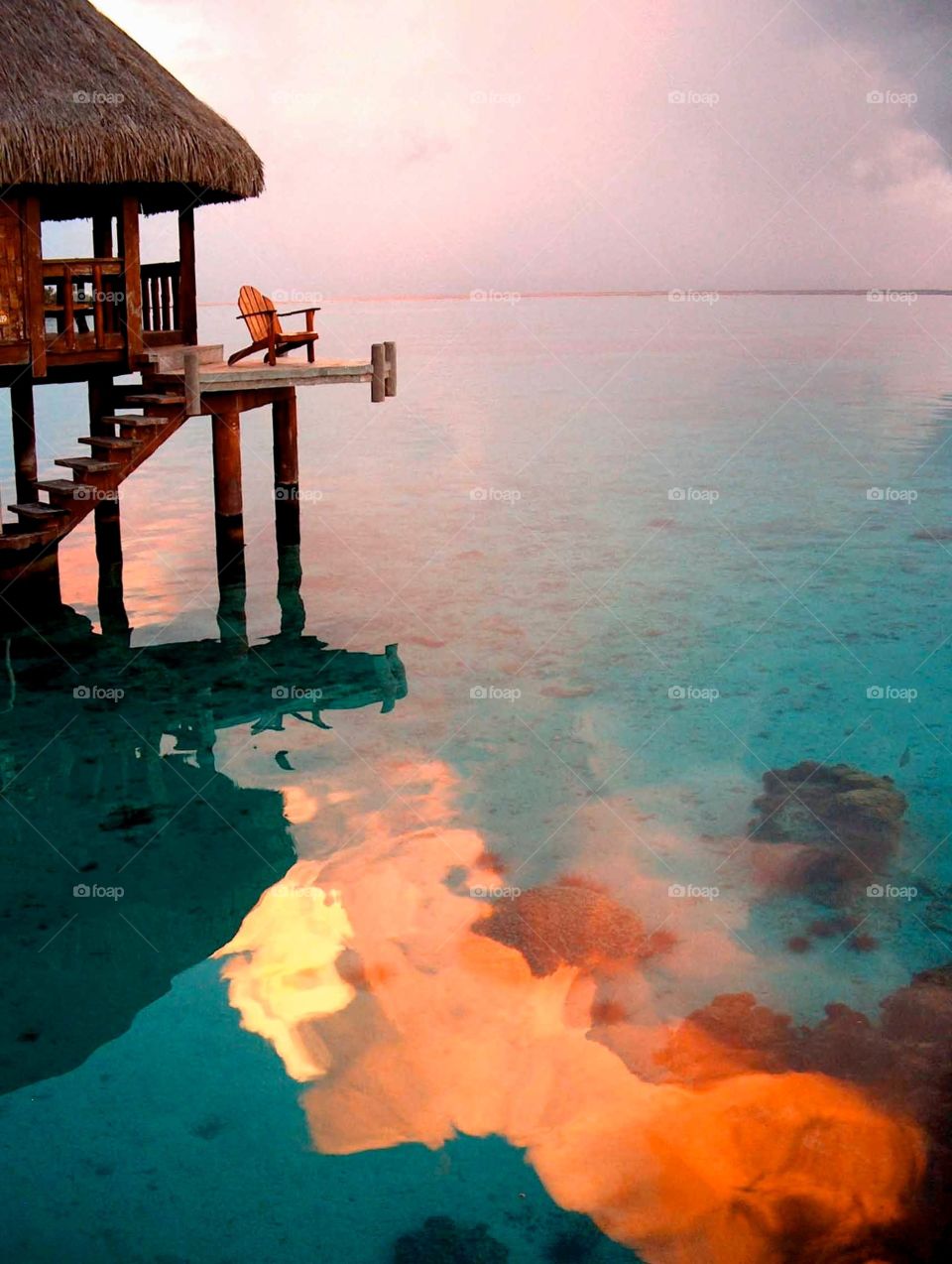 Moorea bungalow at sunset. Moorea bungalow at sunset with cloud reflection in the lagoon