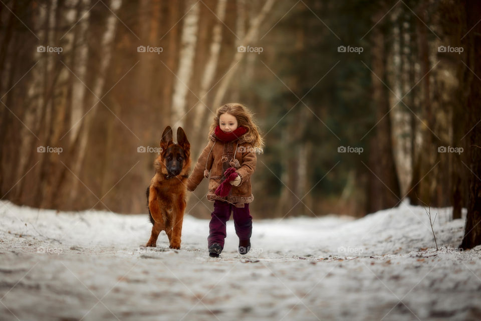 Little girl with German shepherd dog in a spring park 