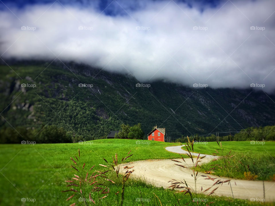 Winding road to a red house at the foot of a mountain 