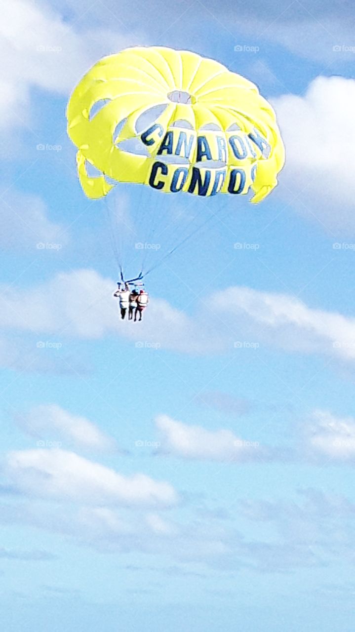 parasailing yellow parachute and three people