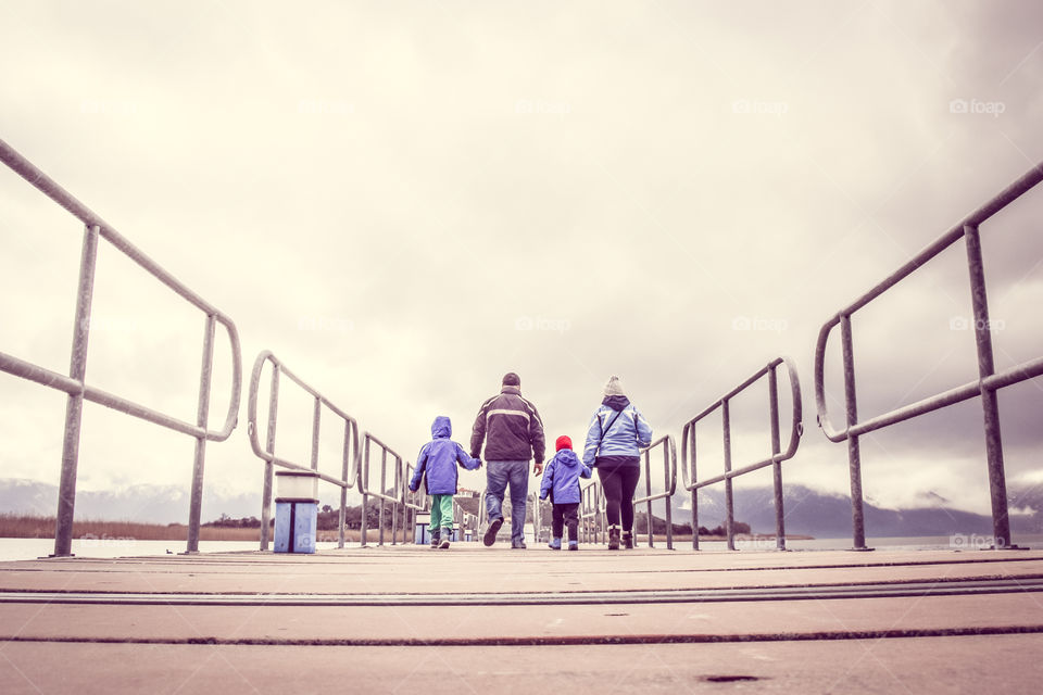 Family On Winter Vacation Walking Across A Bridge Holding Hands
