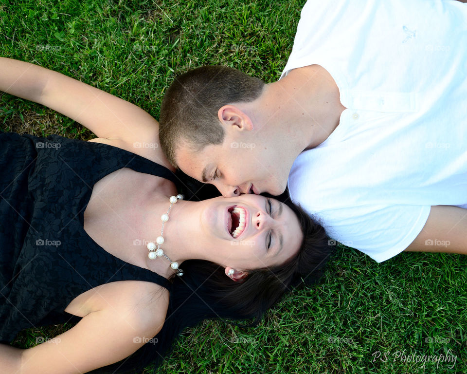 Married couple lying on grass and kissing