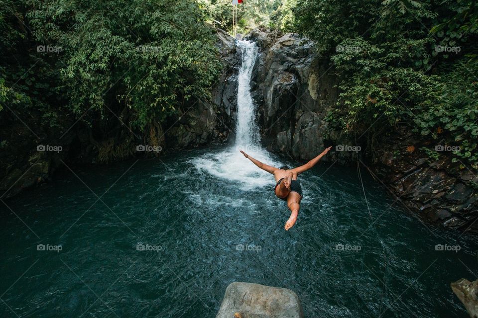 Adventure photo of man diving into tropical waterfall 