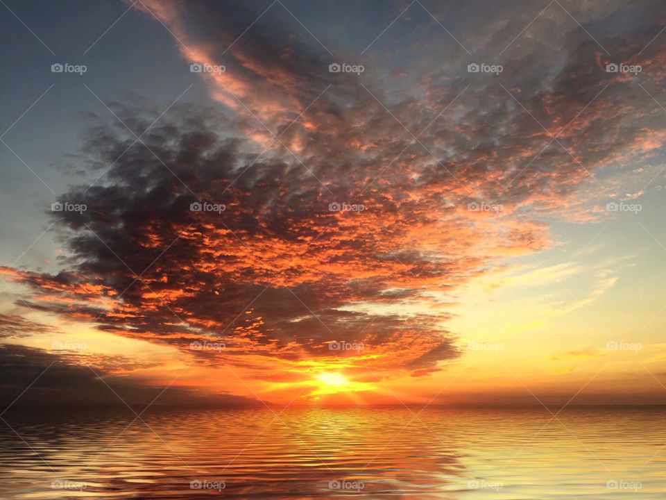Spectacular orange sunset reflecting on a calm sea.