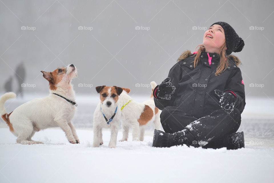Woman sitting snowy land along with dog