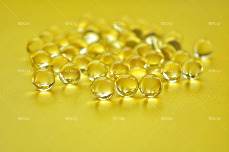 yellow vitamins capsules oils on a yellow background