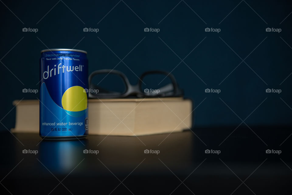 Can of Driftwell on a table with a book and glasses
