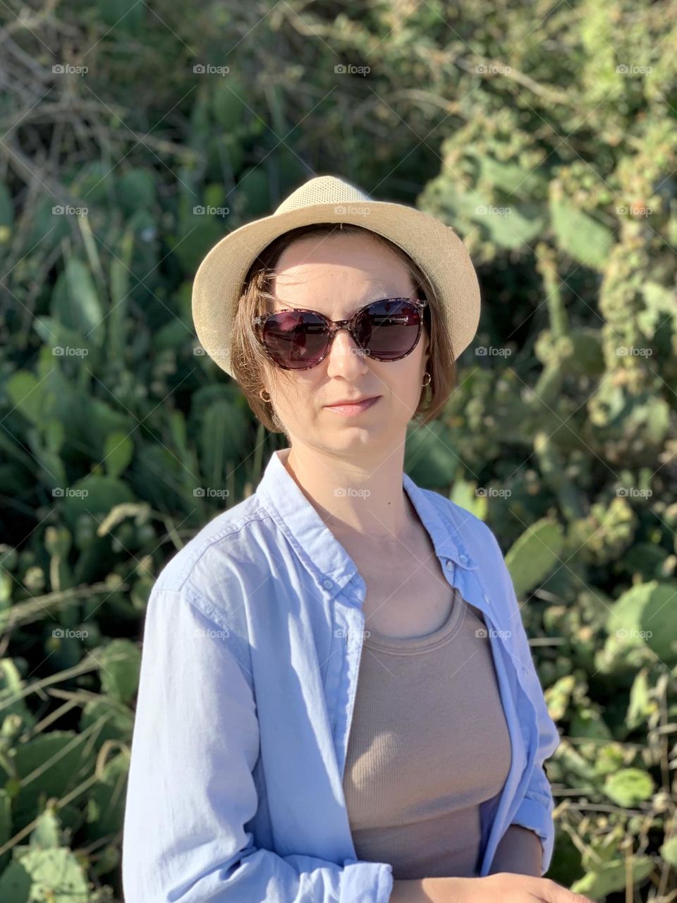 Portrait of a young woman in hat and sunglasses, summer escape, cactus 
