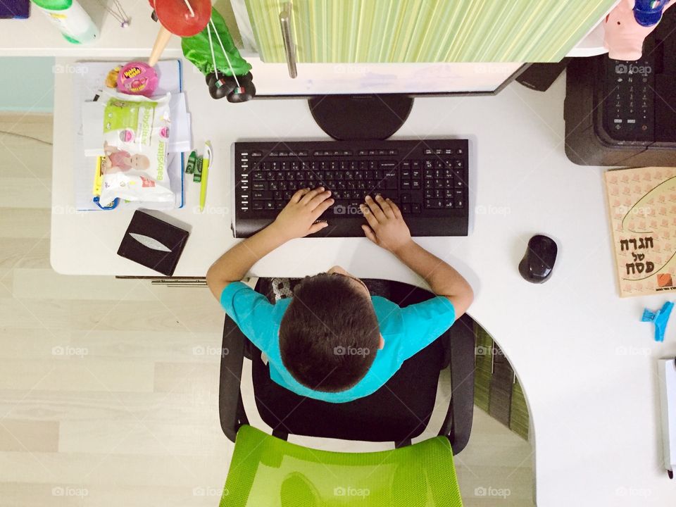 High angle view of boy sitting in front of computer