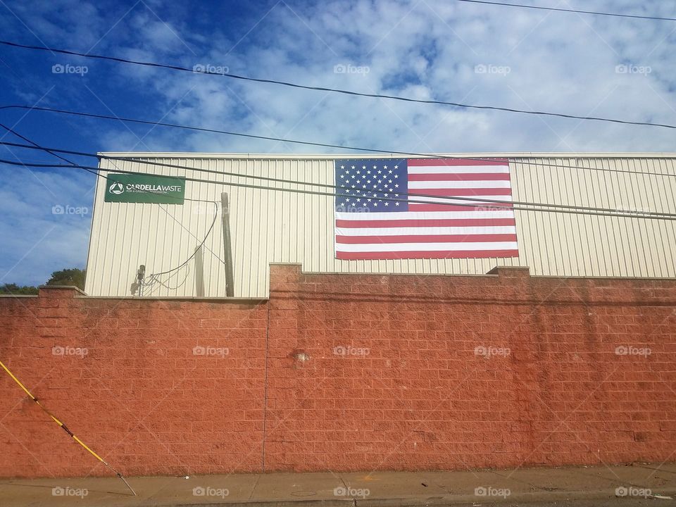Large American flag on the side of a building that belongs to a waste company.