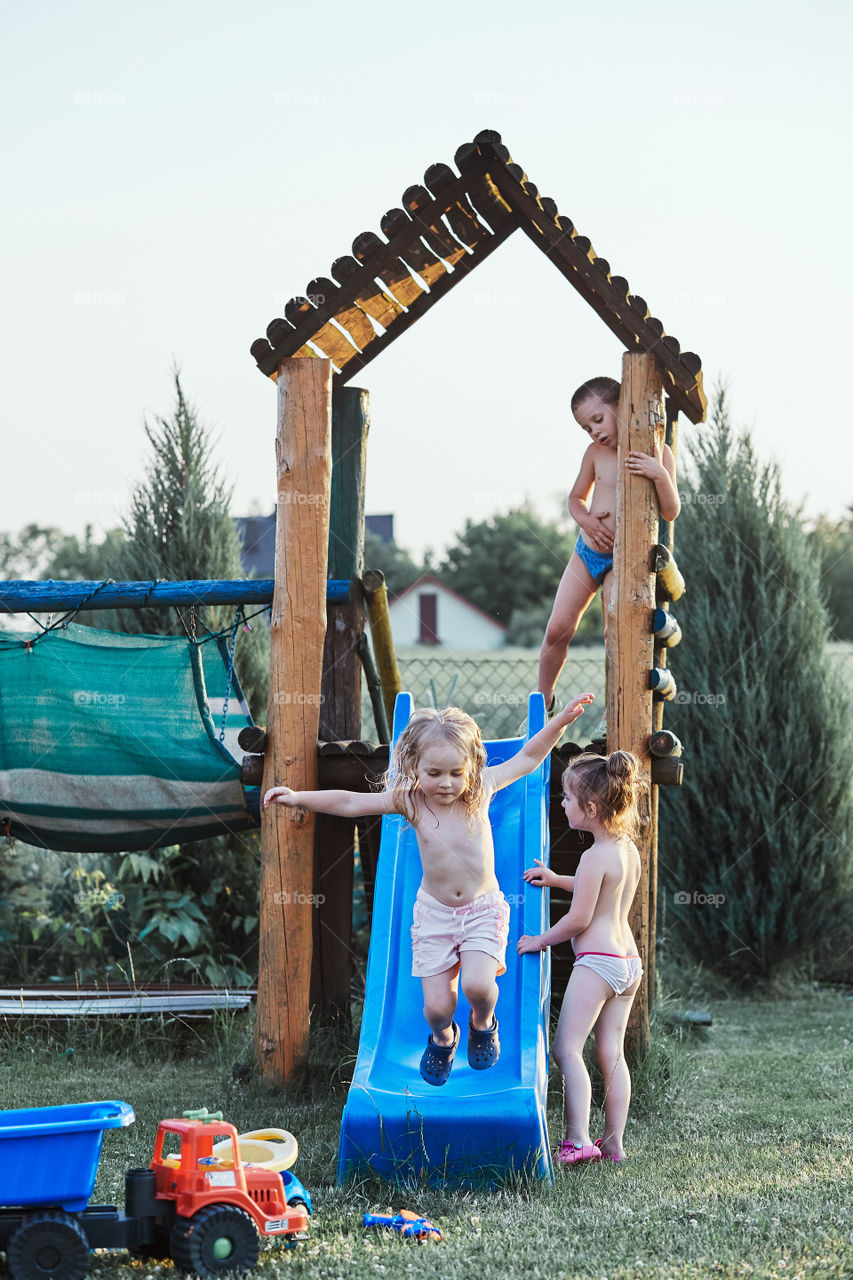 Children playing together in a playground during hot summer vacation day. Candid people, real moments, authentic situations