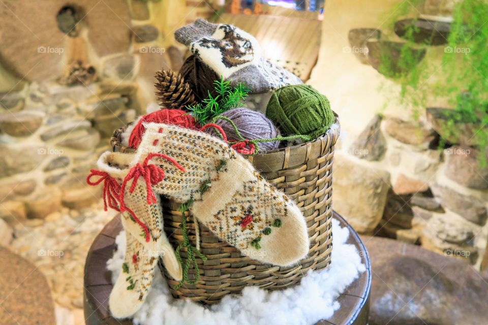 basket with balls of wool yarn and knitted socks and mittens