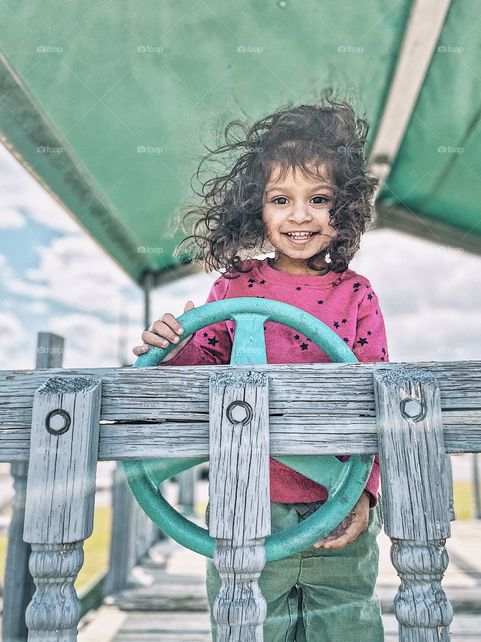 Toddler girl plays on playground, toddler pretend play, playing on a ship playground, toddler at the wheel
