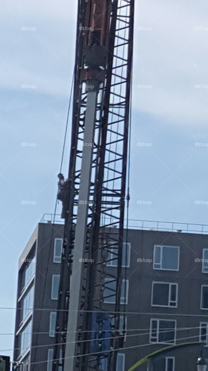 Construction Worker climbing up steel crane