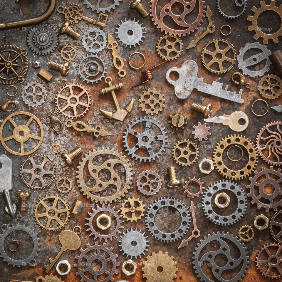 A collection of small metal objects spread out on a rusty metallic background 