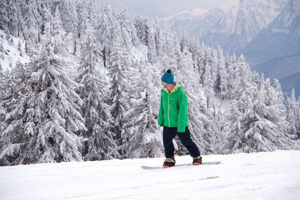 Young man snowboarding in peak Postavarul 