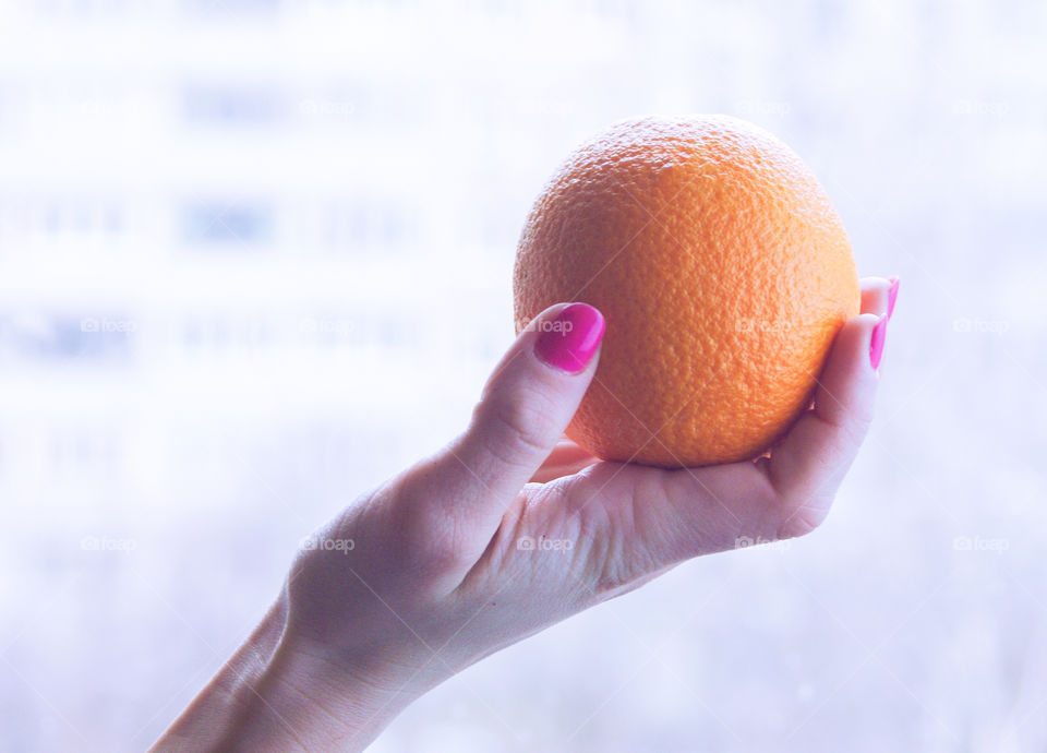 Close-up of hand holding an orange