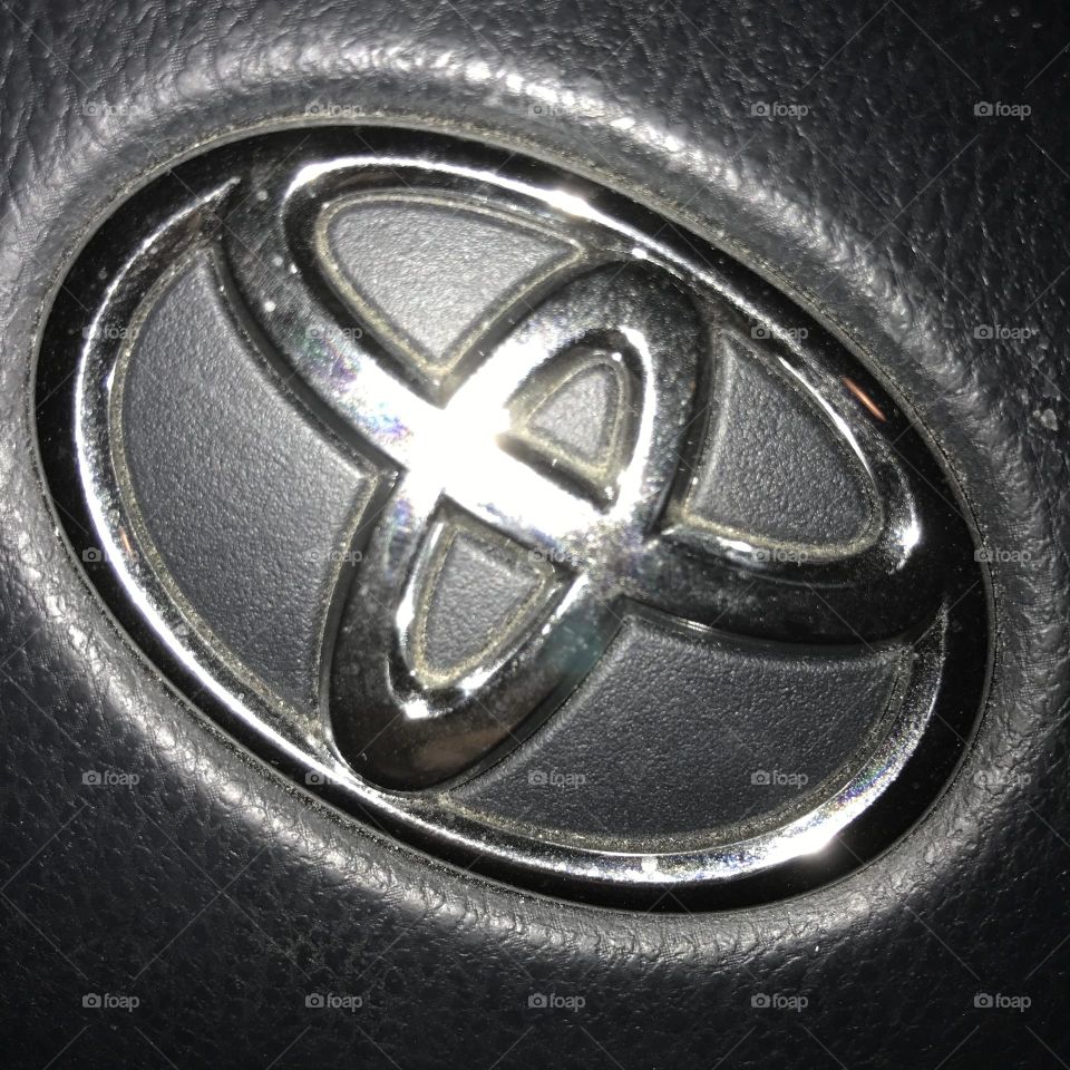 A Toyota logo on the center of a vehicle steering wheel.