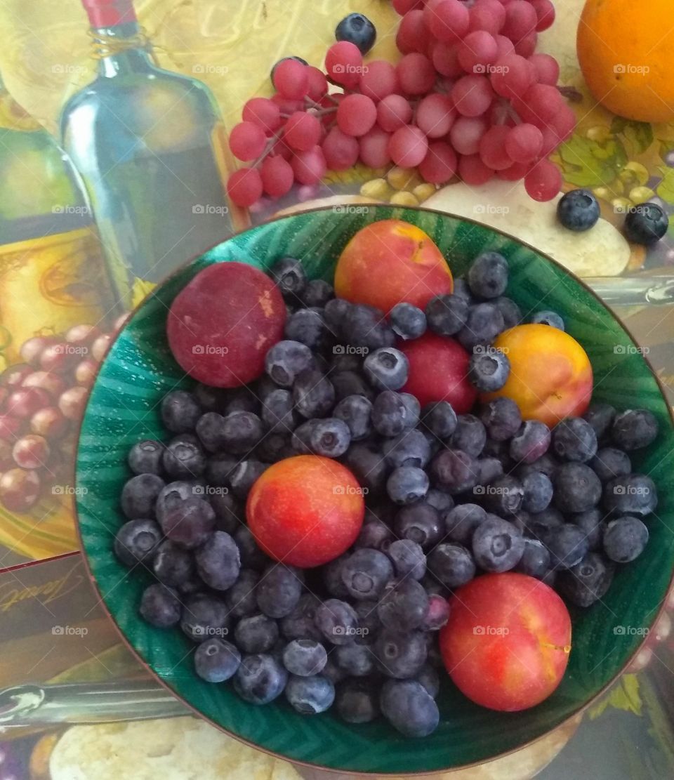 The fruit consists of baby peaches blueberries grapes and a lemon.