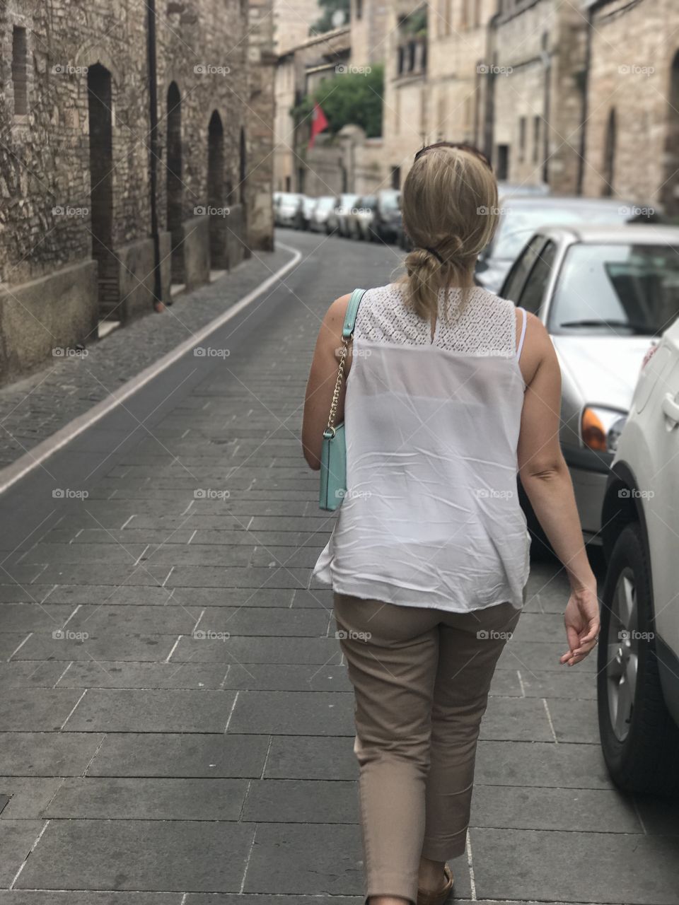 Woman walking down narrow Italian street.